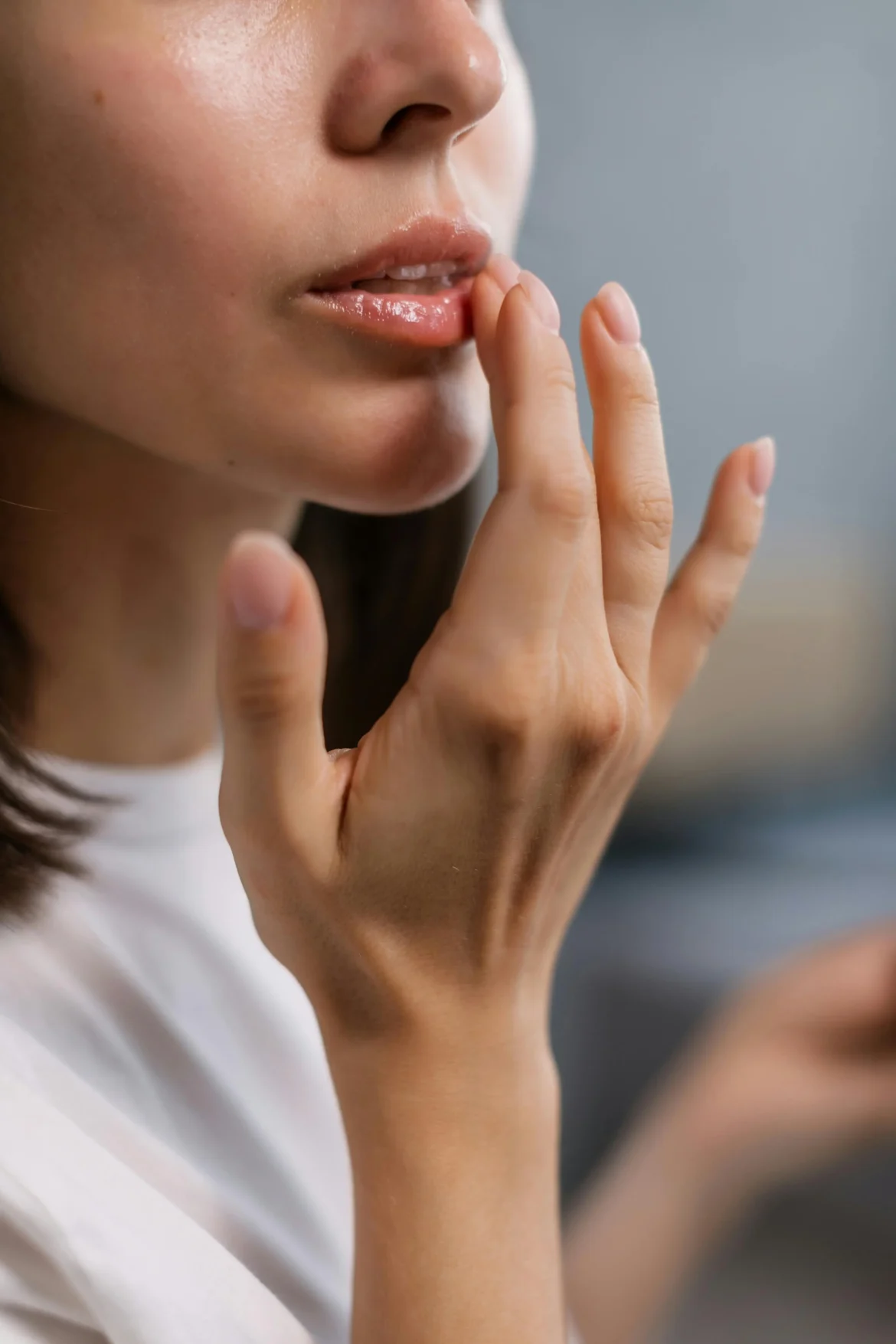 A woman gently applying a hydrating lip balm for soft, nourished lips.